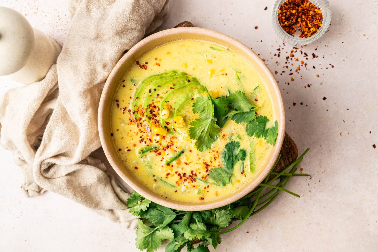 Cream of Corn Soup with Poblanos Creamy corn soup garnished with avocado slices, cilantro, and red pepper flakes.