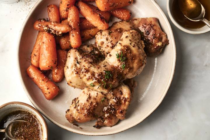 A plate features succulent chicken thighs glazed with mustard and herbs, accompanied by roasted, seasoned carrots.