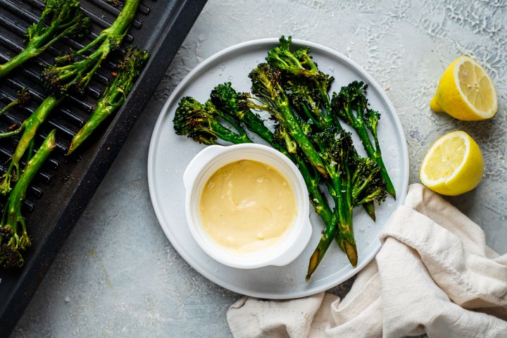 Garlic Grilled Broccolini Garlic grilled broccolini served on a plate with fresh lemon and garlic aioli