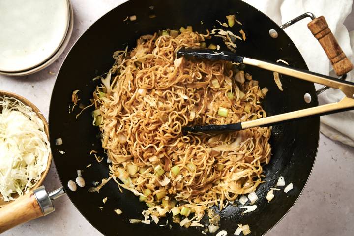Healthy Chow Mein (Panda Express Copycat) Healthy chow mein with cabbage, noodles, and celery in soy sauce in a wok.