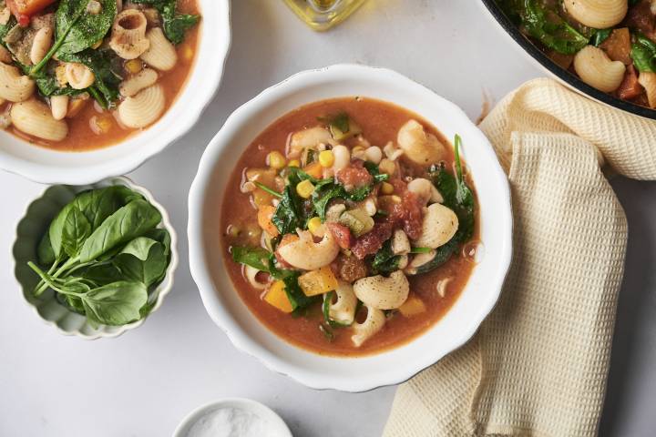 Minestrone Soup A cozy bowl of garden minestrone packed with shell pasta, corn, spinach, white beans, and vibrant vegetables in a savory tomato broth.