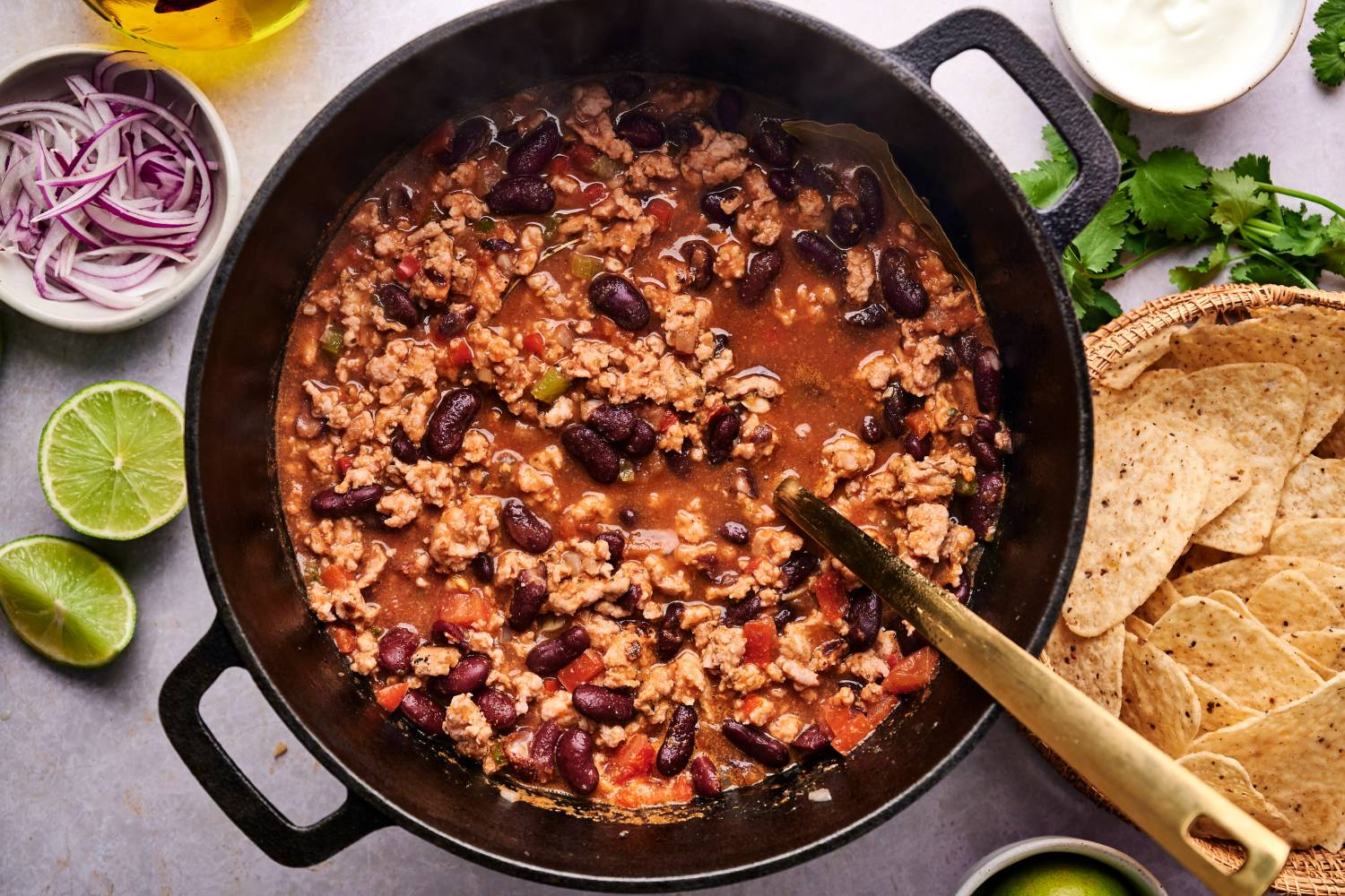 Healthy turkey chili in a soup pot woith ground turkey, kidney beans, peppers, onions, and tomatoes. 