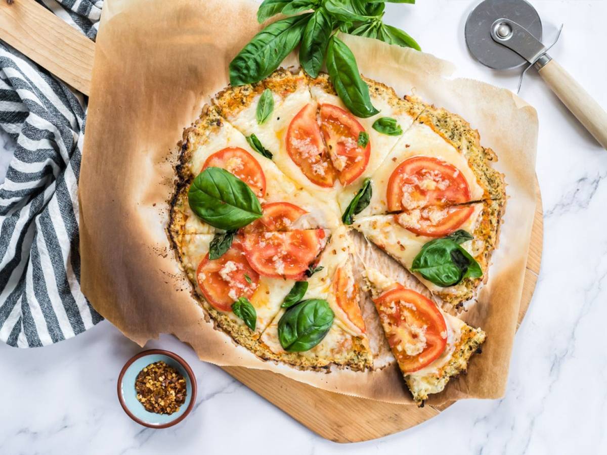 Low Carb Cauliflower crust pizza made with cauliflower florets and topped with mozzarella cheese, tomatoes, and basil for a low carb pizza.