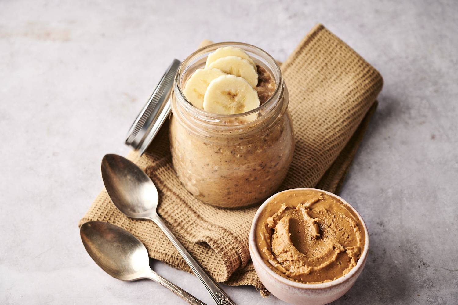 A finished jar of peanut butter banana overnight oatmeal, topped with sliced bananas and chia seeds.