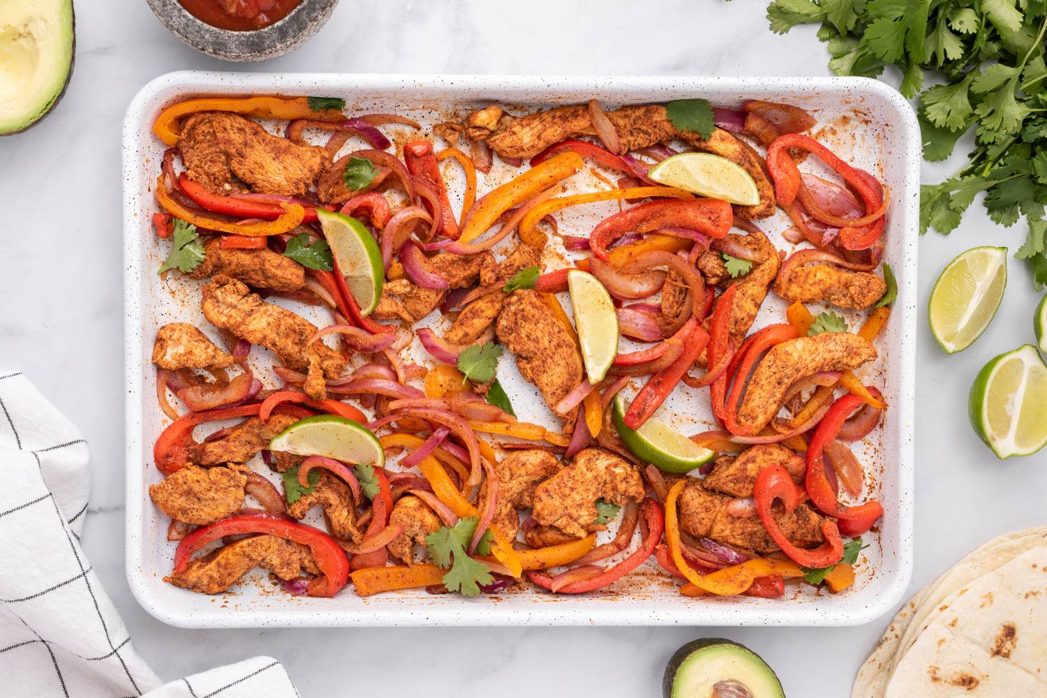 Sheet Pan Chicken Fajitas (5 Ingredients!) Sheet pan chicken fajitas with chicken breast, peppers, onions, and limes on a baking sheet .